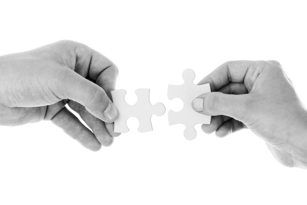 Dwie ręce dokładające do siebie dwa puzzle